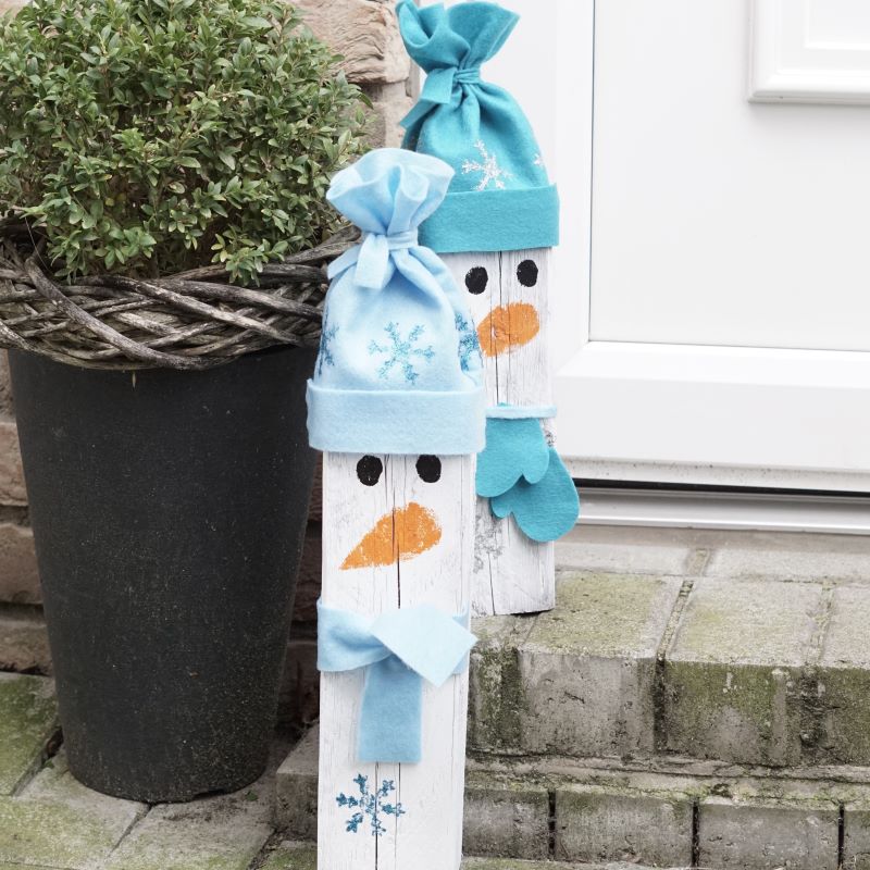 Zwei Schneemann-Türsteher mit Filzmütze und Schal in hellblau und türkis.